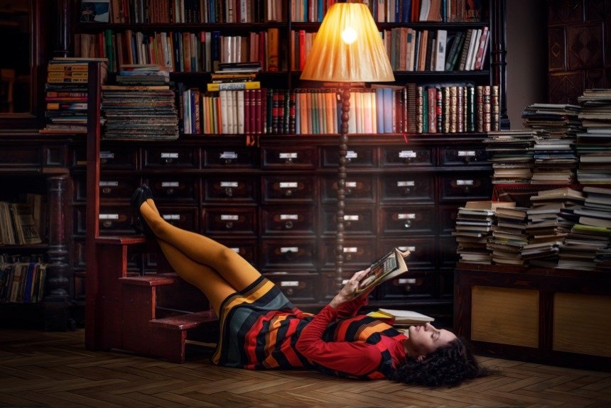 Девушка читает книгу лежа в библиотеке 